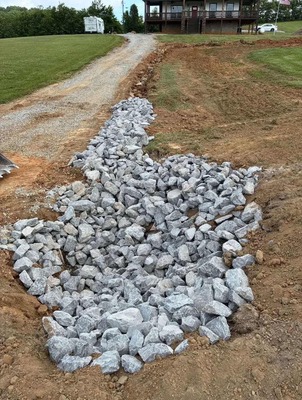 Rip-rap rock drainage channel installed beside a gravel drive in East Tennessee